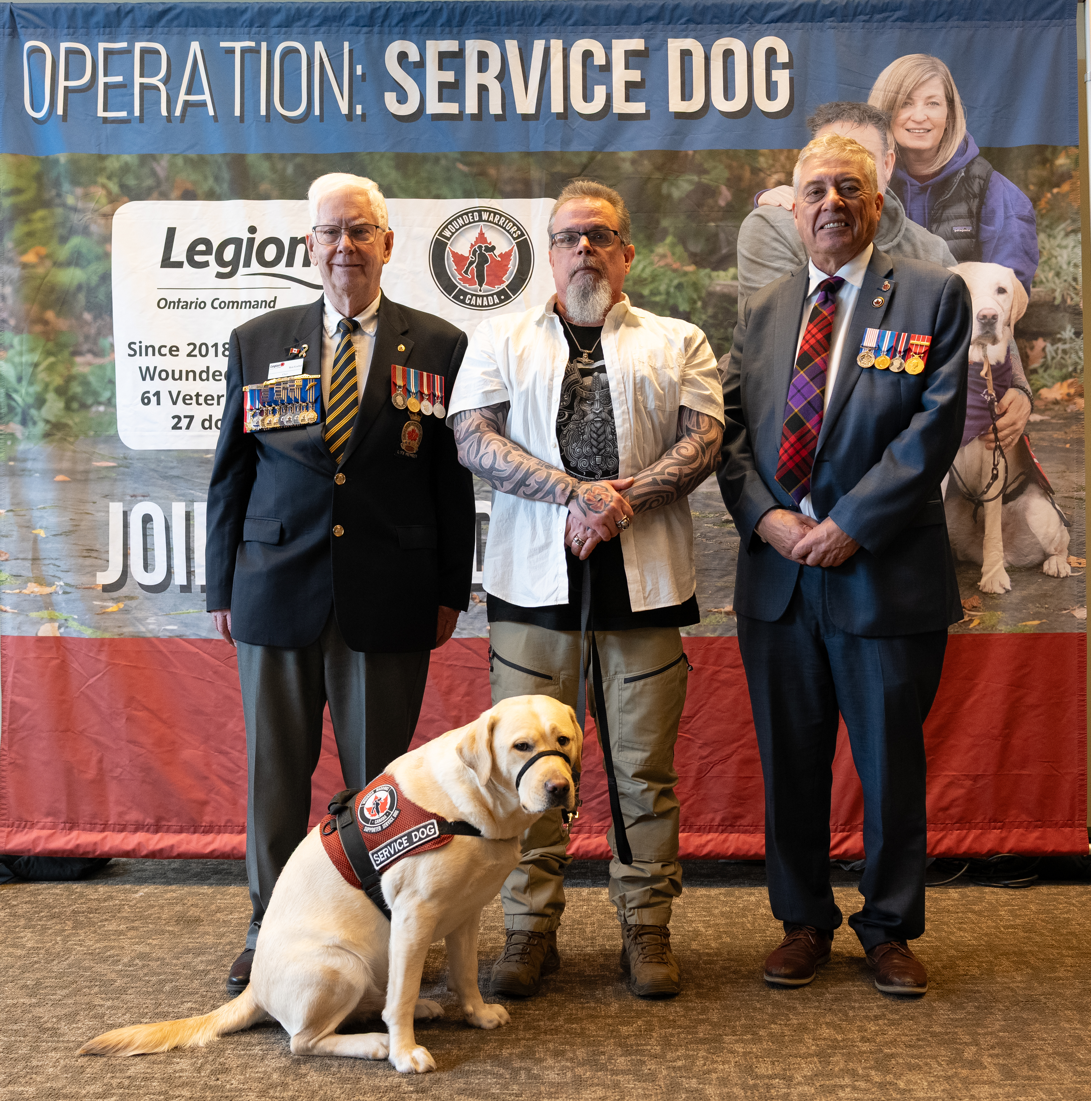 A representative from Ontario Command and Wounded Warriors Canada pose with a Veteran and his dog for a photo