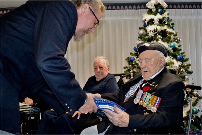 quilts Legion Branch 228 member Brendan McGynn presents a special one-of-a-kind quilt to retired veteran John Mylod, at the Stirling Manor Nursing Home as fellow recipient Albert Seaborn looks on.