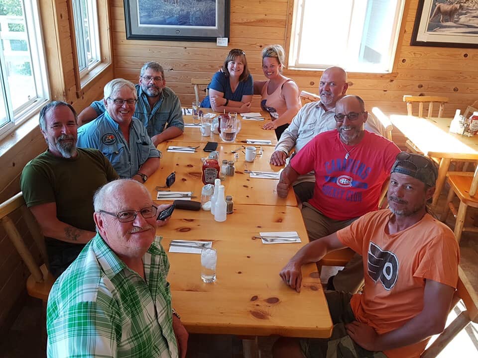 A group of people sitting at a table looking at the camera.